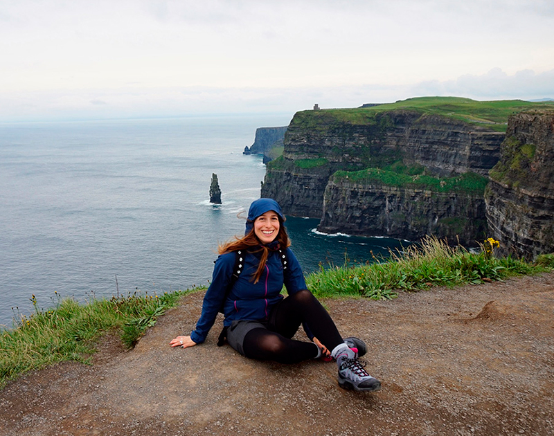 Woman happily Hiking at the Cliffs of Moher in Ireland